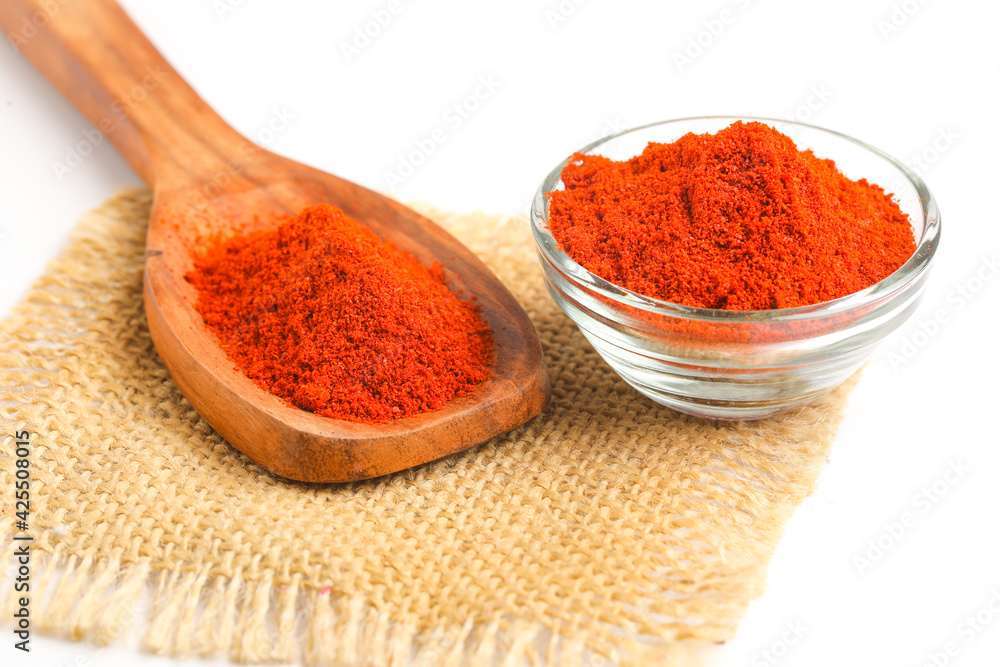 close view of red chilli powder in wooden spoon on white background. close view of red chilli powder in wooden spoon on white background.