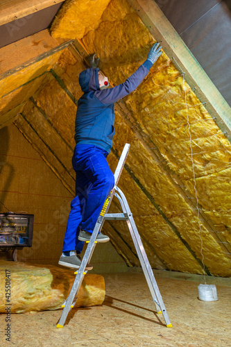 The man insulates the attic of the house with mineral wool photo