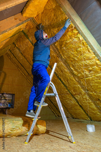 Foto The man insulates the attic of the house with mineral wool