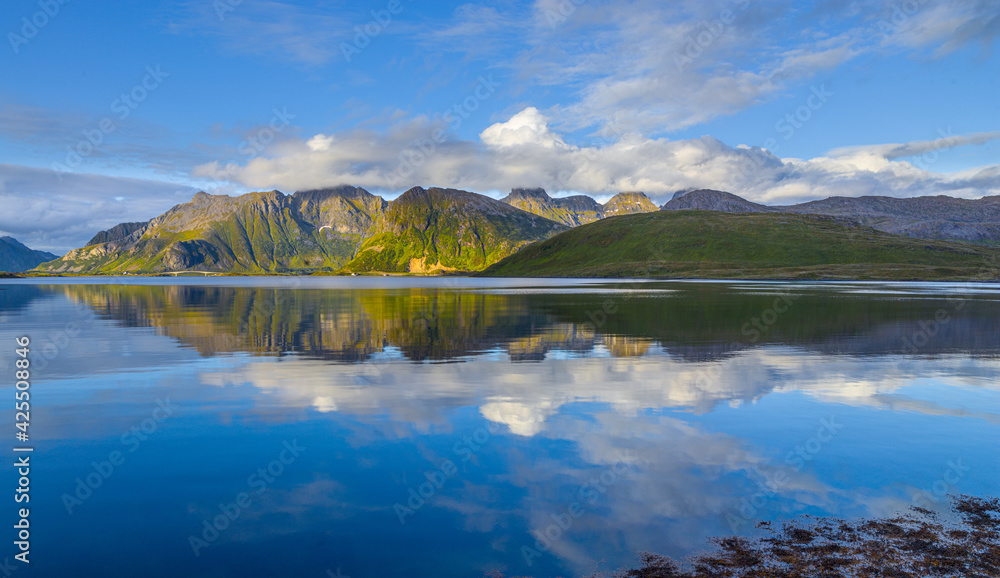 Fjord landscape with reflection of mountains on the Lofoten in northern Norway in panorama format