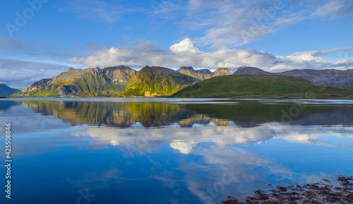 Fjord landscape with reflection of mountains on the Lofoten in northern Norway in panorama format