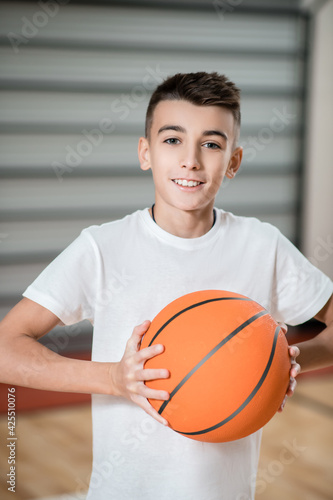 A boy playing basketball in the gym and looking involved
