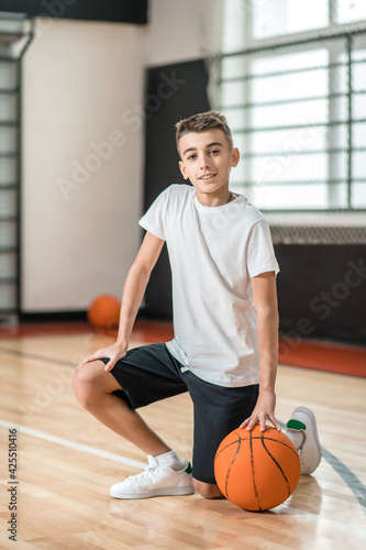 A dark-haired boy playing with a ball in the gym