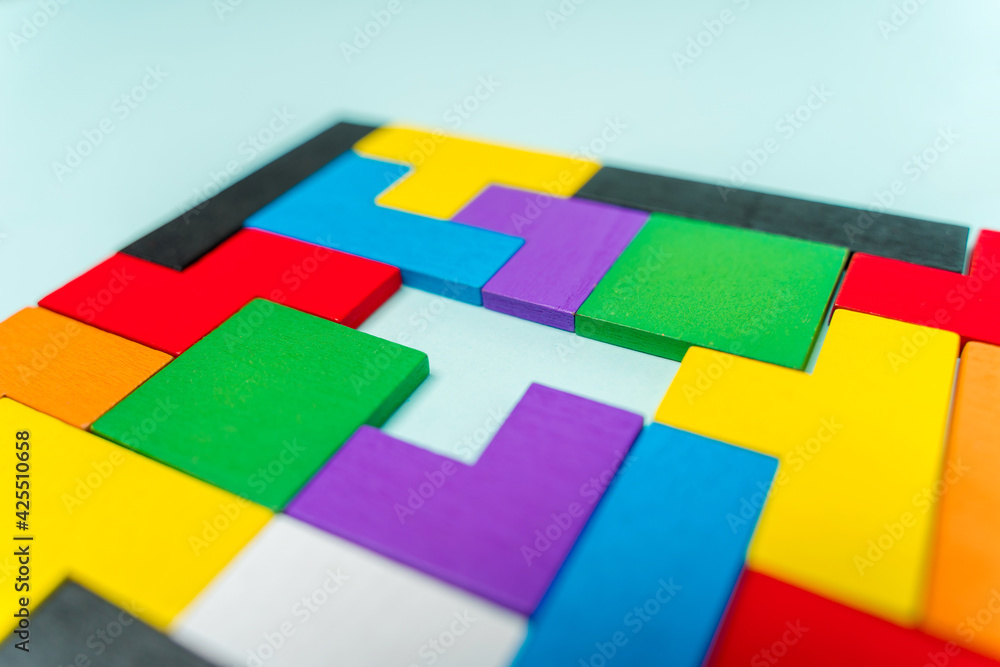 Geometric shapes made of wood in different colors on a blue background with a missing shape, background image with space for text Geometric shapes made of wood in different colors on a blue background with a missing shape, background image with space for text