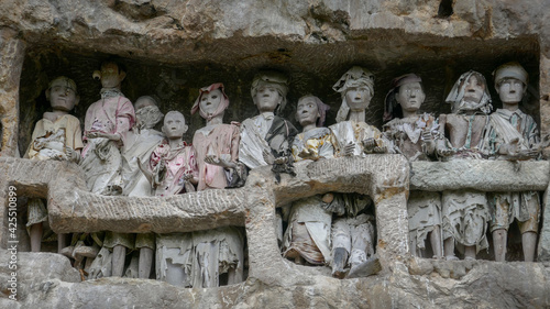 Tau tau or wooden effigies of the deceased guarding their graves built inside cliff in Suaya traditional village, Tana Toraja, South Sulawesi, Indonesia photo