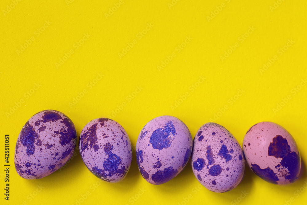Line of purple colored quail eggs in bottom on yellow background. Easter concept. Line of purple colored quail eggs in bottom on yellow background. Easter concept.