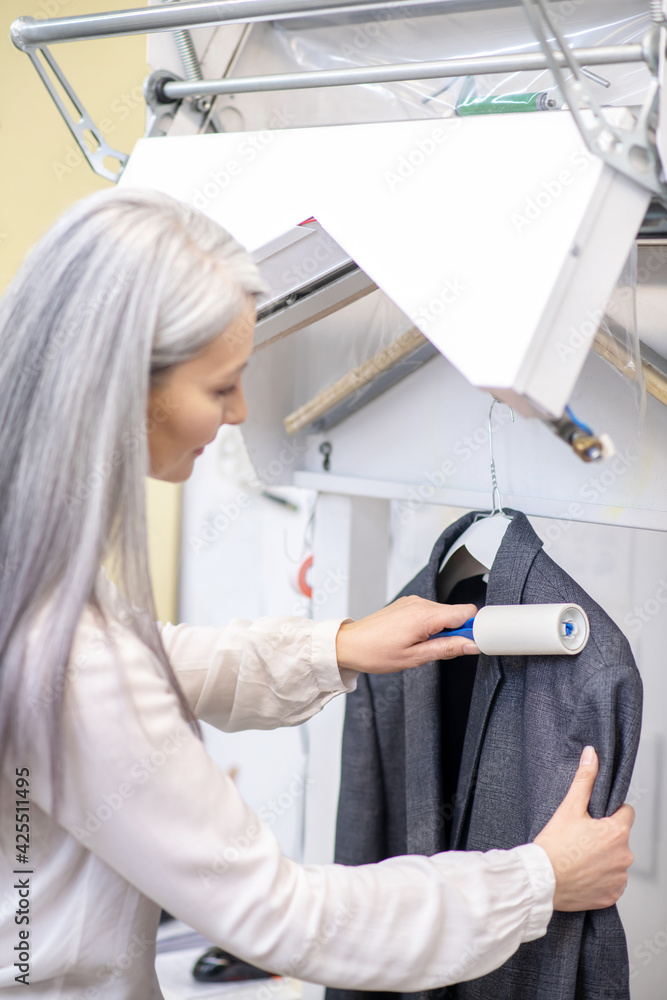Attentive woman in white blouse cleaning jacket Attentive woman in white blouse cleaning jacket
