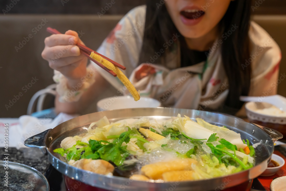 Women use chopsticks Catch baby corn feel happy and enjoy For sukiyaki pot ( hot pot ) Women use chopsticks Catch baby corn feel happy and enjoy For sukiyaki pot ( hot pot )