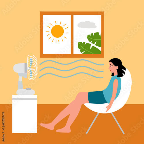 Woman sitting in her house in front of an electric fan. She exhausted of hot summer day. Sweaty and thirsty.