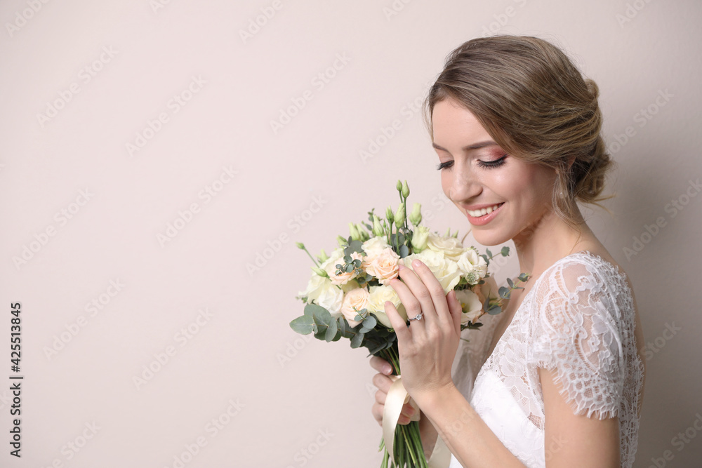 Young bride with beautiful wedding bouquet on beige background. Space for text