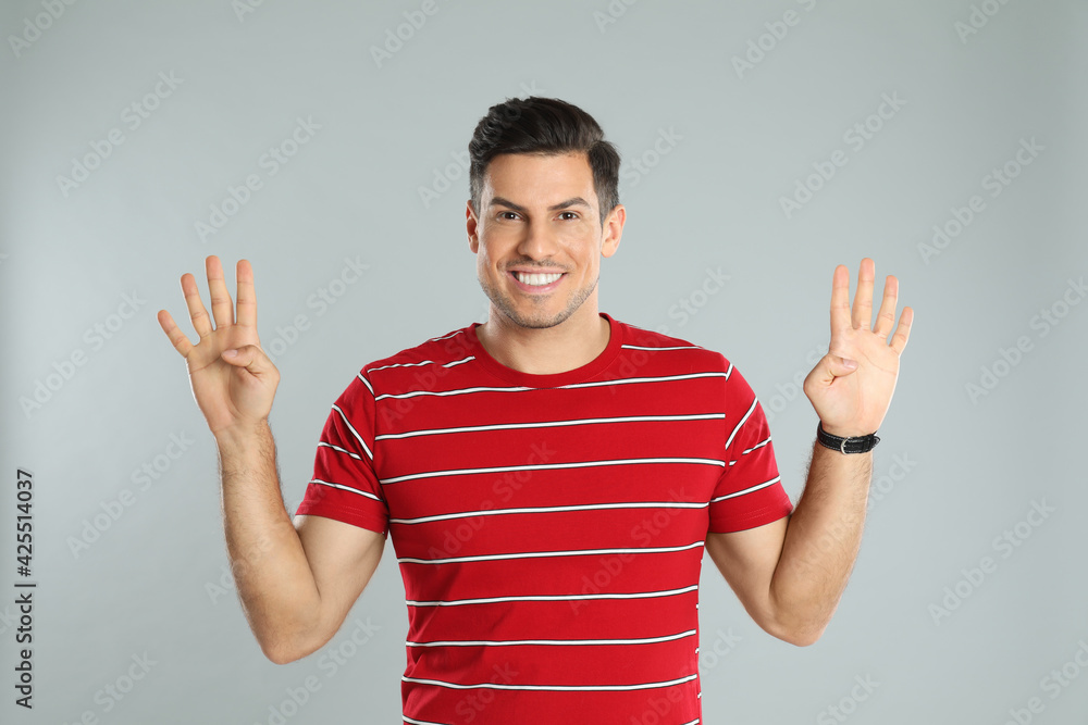 Man showing number eight with his hands on grey background Man showing number eight with his hands on grey background