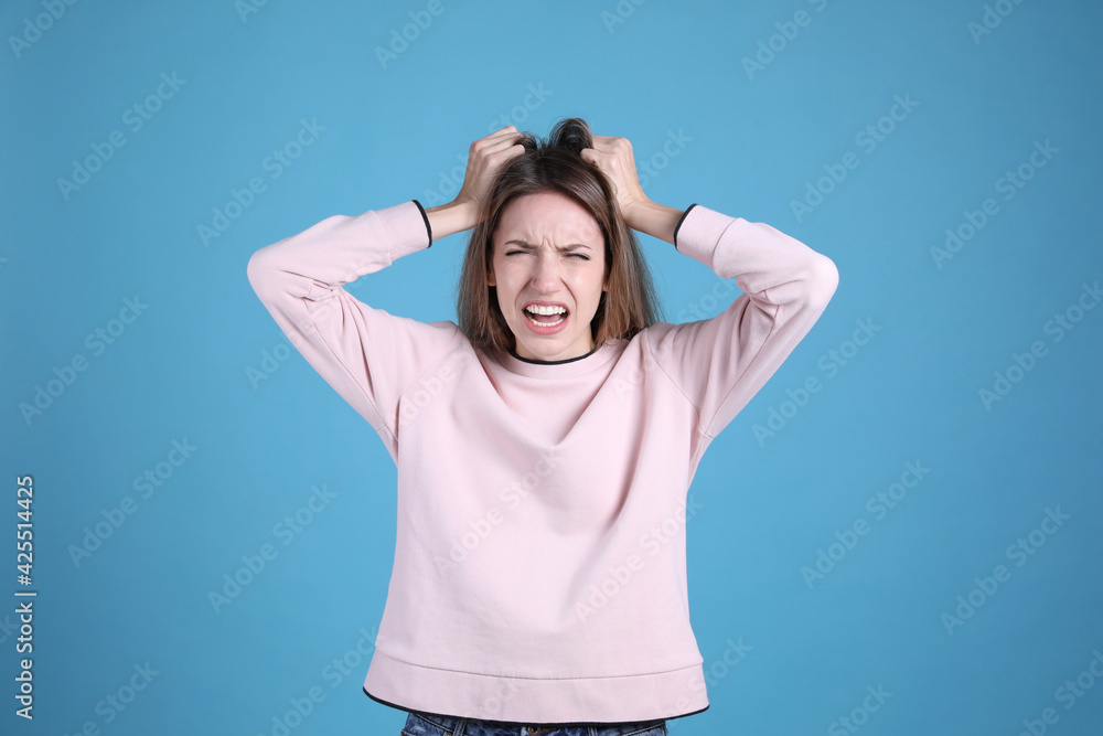 Portrait of stressed young woman on light blue background Portrait of stressed young woman on light blue background