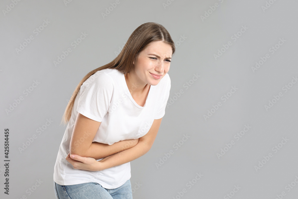 Woman suffering from stomach ache on grey background, space for text. Food poisoning Woman suffering from stomach ache on grey background, space for text. Food poisoning