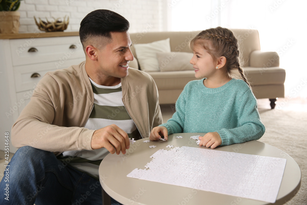 Happy father and his daughter playing with puzzles at home Happy father and his daughter playing with puzzles at home