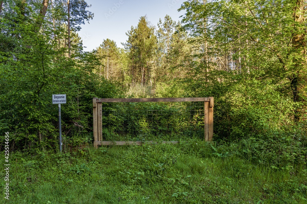 Closed gate with a sign: Deponie Betreten verboten (German for: Landfill, do not enter), seen in a forest in Ratingen, North Rhine-Westphalia, Germany