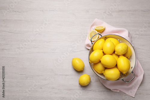 Many fresh ripe lemons on wooden table, flat lay. Space for text