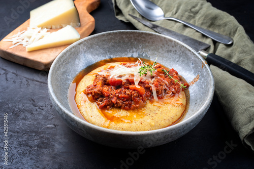 Modern style traditional Italian polenta alla sarda con salsiccia with ground meat ragu and pecorino served as close-up on a Nordic design bowl photo