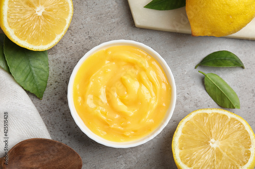 Delicious lemon curd in bowl on grey table, flat lay photo