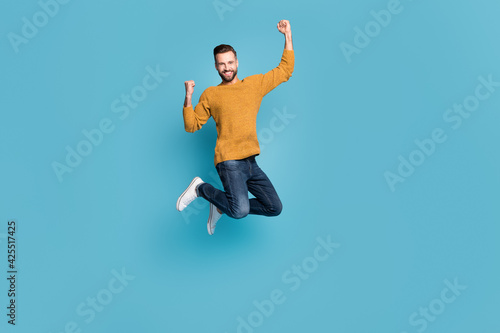 Full length body size view of nice lucky cheerful motivated guy jumping celebrating having fun isolated on bright blue color background