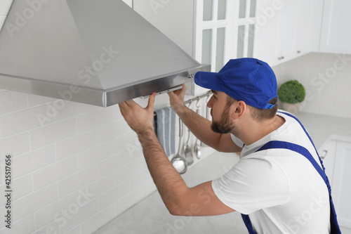 Cuadro en lienzo Worker repairing modern cooker hood in kitchen