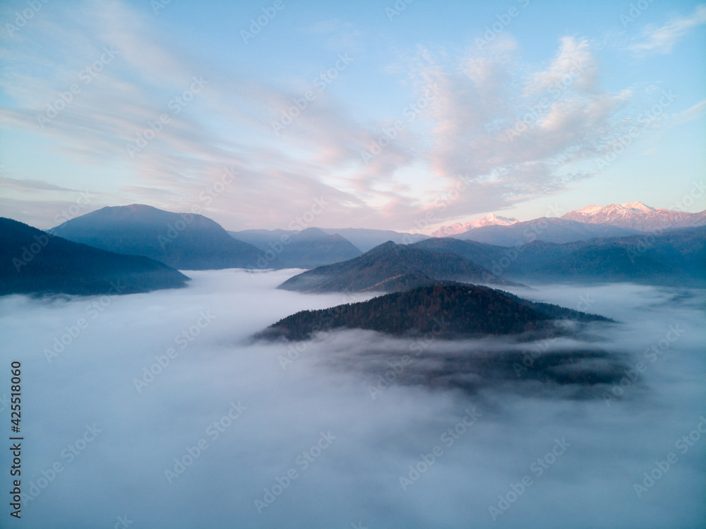 Aerial view, sea of fog and clouds illuminated by the rising sun, snow on the tops of the mountains. Russia Aerial view, sea of fog and clouds illuminated by the rising sun, snow on the tops of the mountains. Russia