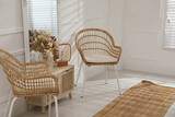 Living room interior with wooden commode, mirror and wicker chairs