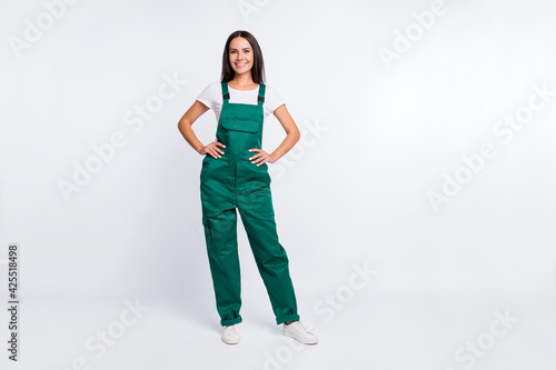 Photo of pretty positive lady hands hips look camera wear green overall isolated white color background photo