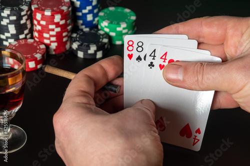 Poker cards two pairs combination. Close up of a gambler hand is holding playing cards and sigar in poker club photo