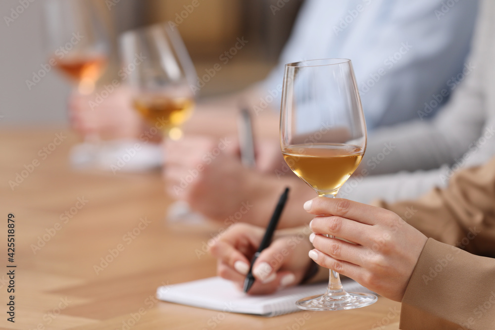 Sommeliers tasting different sorts of wine at table indoors, closeup