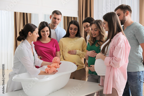 Pregnant women with men learning how to bathe baby at courses for expectant pare Fototapeta