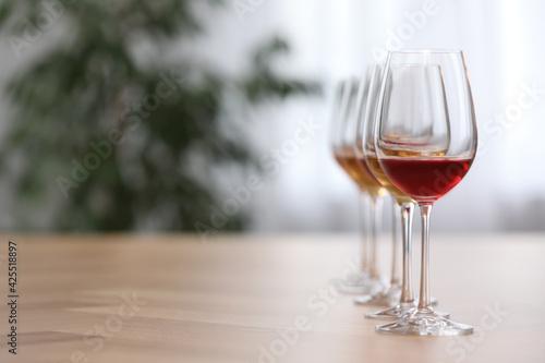 Different sorts of wine in glasses on wooden table indoors. Space for text