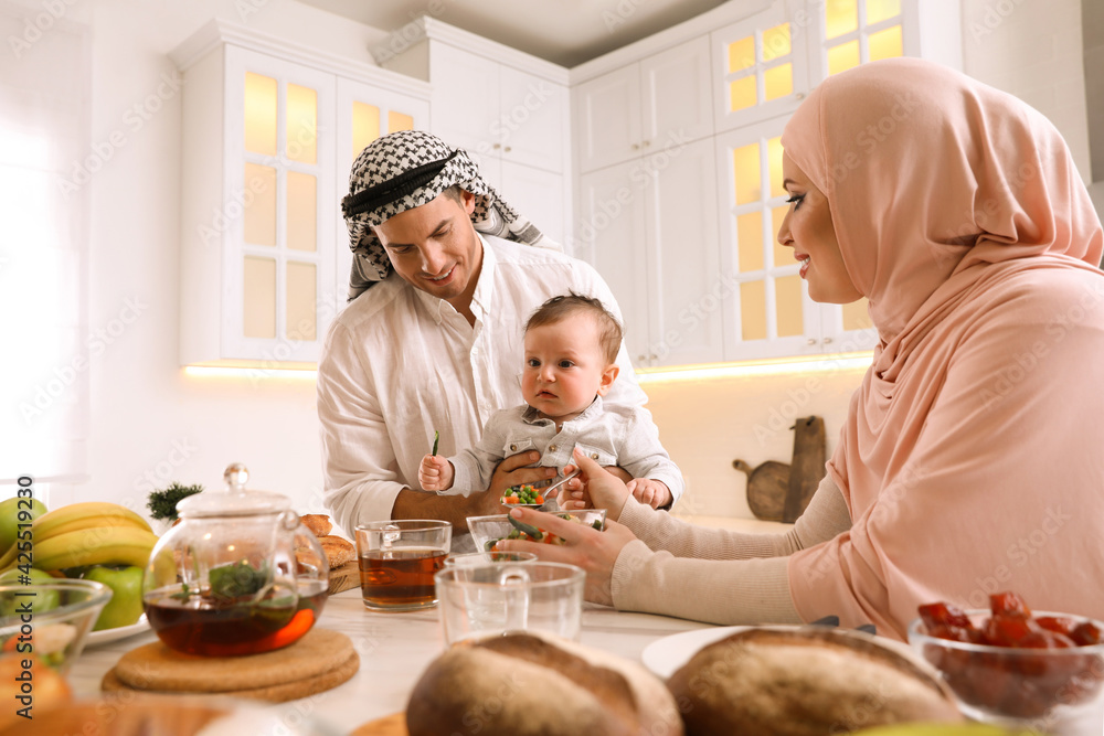Happy Muslim family with little son at served table in kitchen Happy Muslim family with little son at served table in kitchen