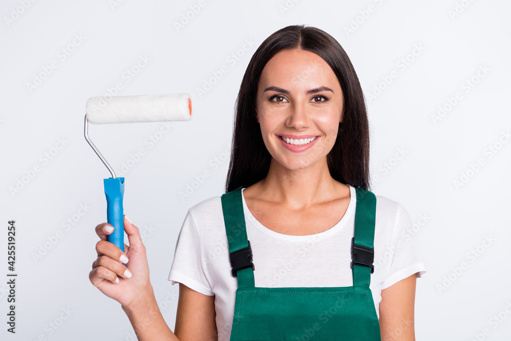 Photo of worker painter lady hold roller toothy smile look camera wear green overall isolated white color background Photo of worker painter lady hold roller toothy smile look camera wear green overall isolated white color background