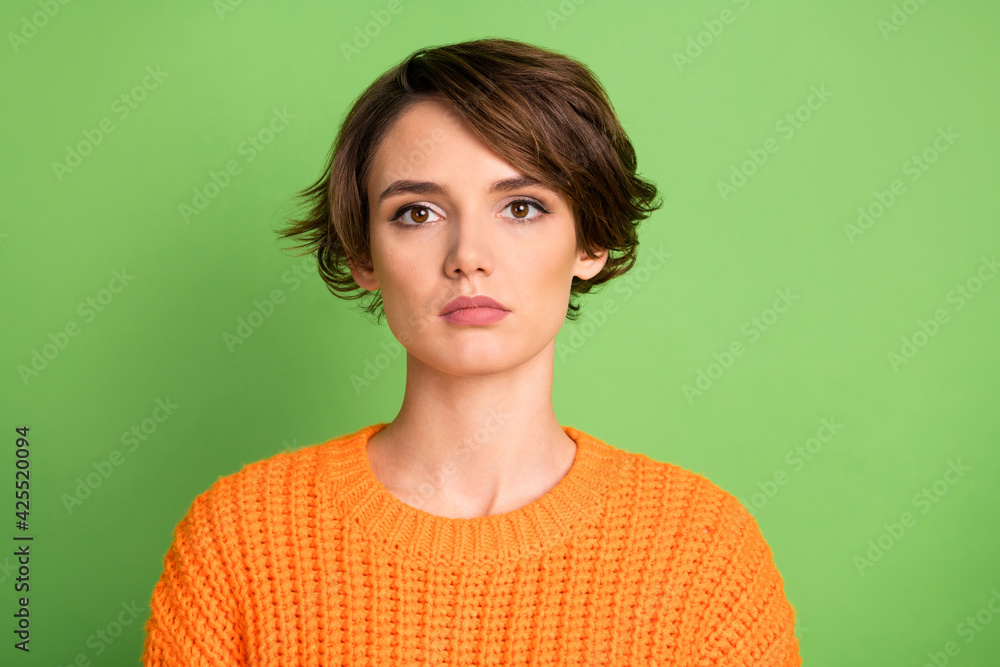 Portrait of young attractive pretty charming serious woman in orange knitted jumper isolated on green color background Portrait of young attractive pretty charming serious woman in orange knitted jumper isolated on green color background