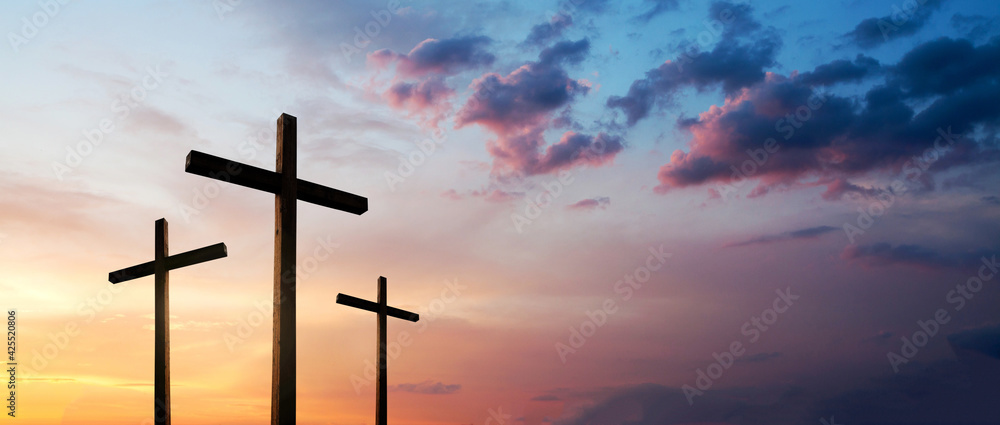 Easter concept. Cross of Jesus Christ empty over dramatic sunrise sky panorama with sclouds.