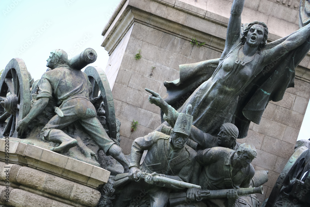 dark green war memorial depicting soldiers fighting and a screaming woman