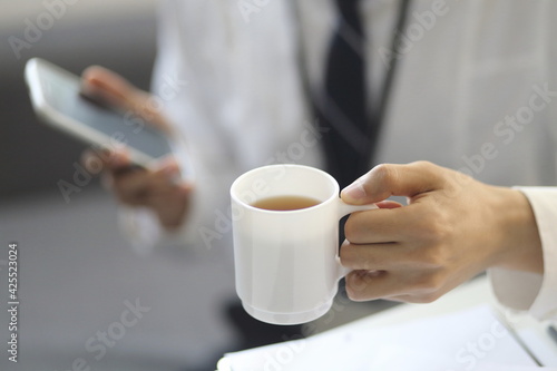 Businessman drinking coffee with smartphone 