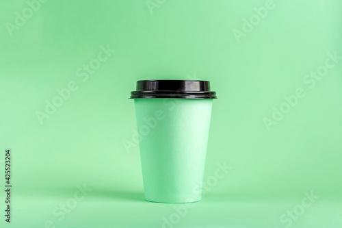 Disposable Eco Paper Cup with coffee on green background. Mockup for advertising. Coffee to go, take away concept. Copy space for text.