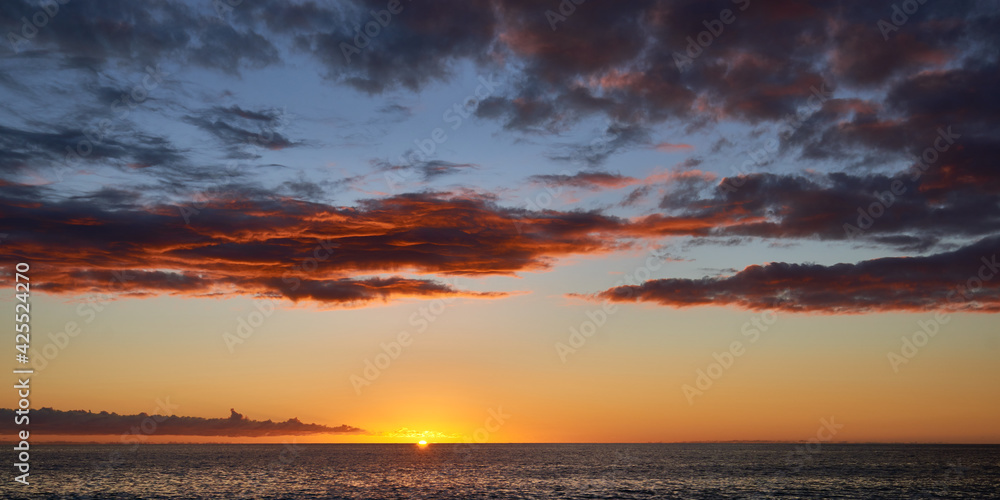 Panoramic view of the dramatic sunset sky with dark clouds over ocean in Hawaii.
