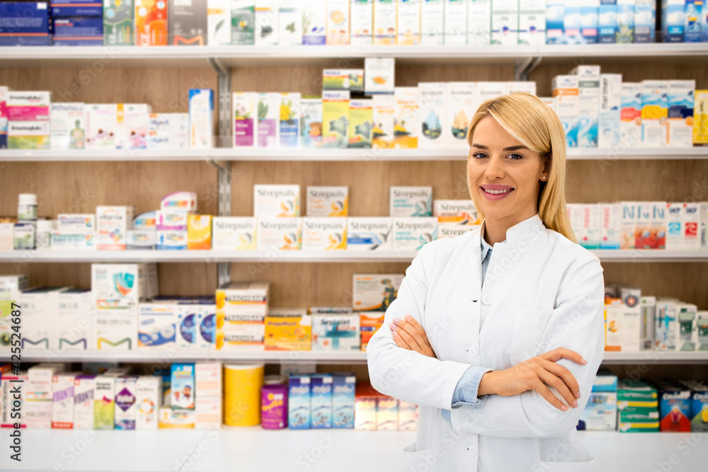 Portrait of smiling female caucasian pharmacist standing in drug store with arms crossed.