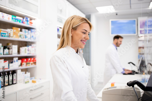 Female caucasian pharmacist selling medicines in pharmacy store.