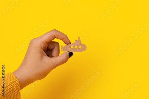 wooden submarine in hand over yellow background