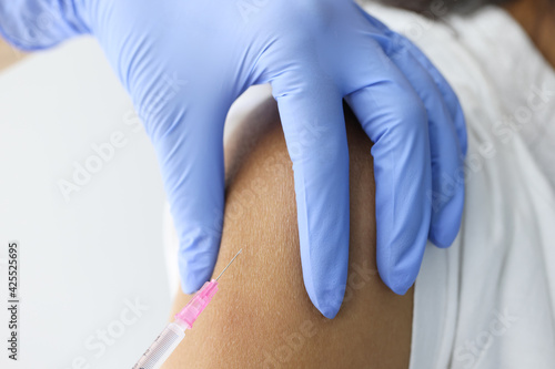 Doctor injecting medicine in patient shoulder closeup