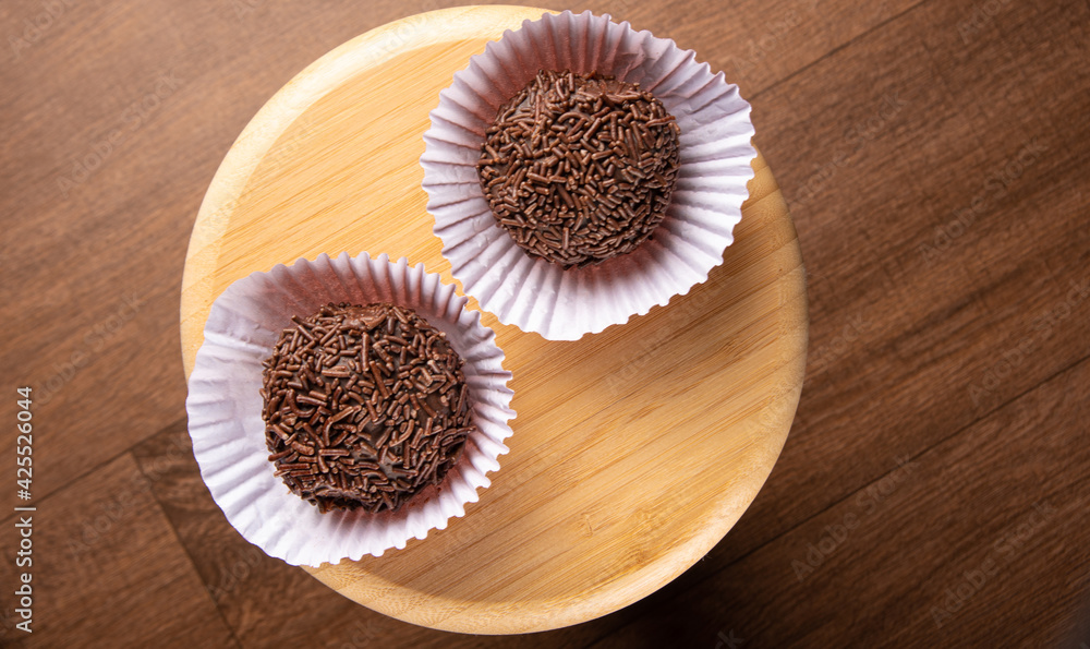 Brigadeiros, traditional Brazilian sweet in detail on wooden surface, black background, top view. Brigadeiros, traditional Brazilian sweet in detail on wooden surface, black background, top view.