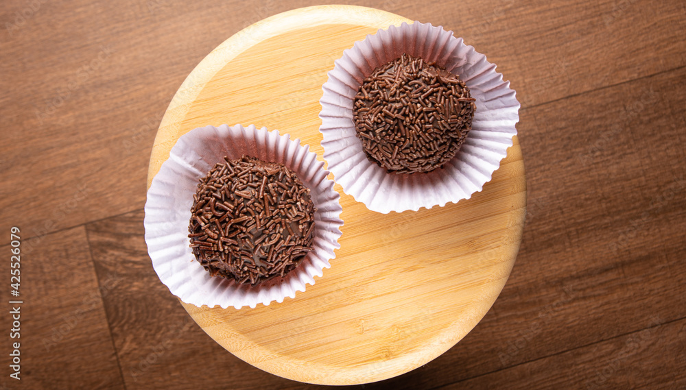 Brigadeiros, traditional Brazilian sweet in detail on wooden surface, black background, top view.
