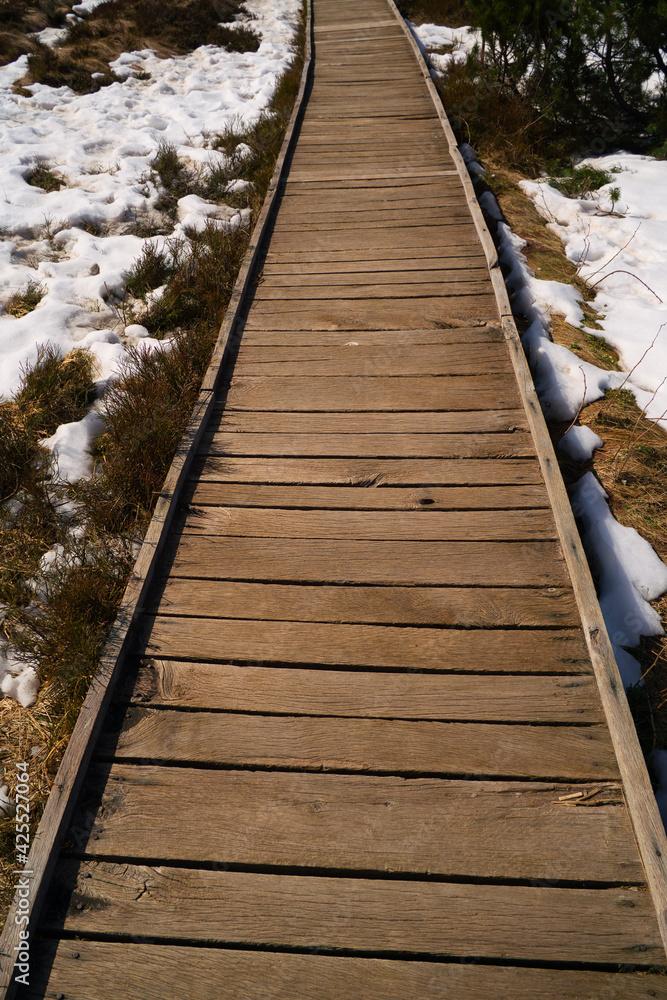 a beautiful wooden footbridge in the high moor with snow in spring