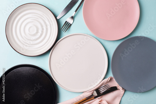 Some different empty plates with tableware on blue background photo