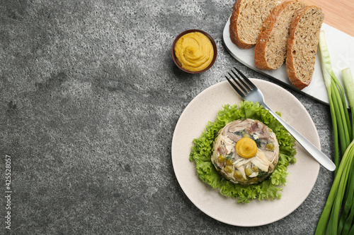 Fotografie Delicious aspic with meat and vegetables served on grey table, flat lay