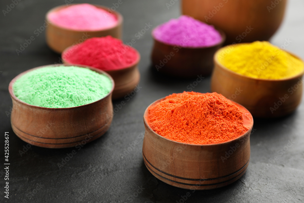 Colorful powder dyes in bowls on black background, closeup. Holi festival Colorful powder dyes in bowls on black background, closeup. Holi festival