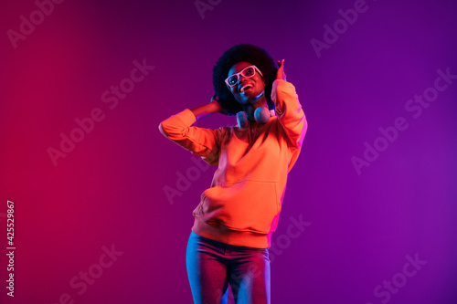 Photo of cute dreamy lady have fun look up empty space wear hoodie headphones eyewear isolated gradient dark background